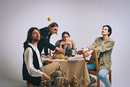 Vier Bandmitglieder sitzen am gedeckten Tisch