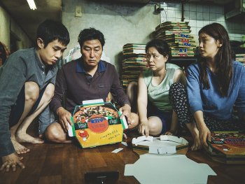 Copyright: Koch Films Eine vierköpfige Familie (Vater, Mutter, Tochter und Sohn) sitzen auf dem Boden und falten Pizzakartons.