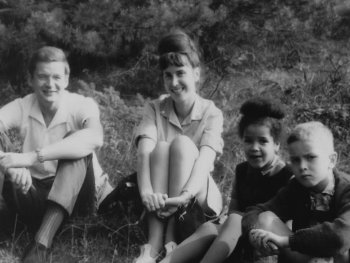 Schwarzweiß Foto einer vierköpfigen Familie, die auf einer Wiese sitzt.