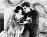 Schwarzweiß-Foto. Ein Soldat liest einer Frau aus einem Buch vor.