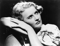 Schwarzweiß-Foto. Ein Frau sitzt auf einem Stuhl und schaut nach oben.