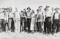 Schwarzweiß-Foto. In der Mitte einer Menschenmenge geben sich eine Frau und ein Mann die Hand.