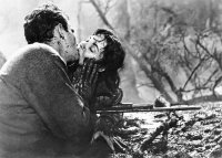 Schwarzweiß-Foto. Eine Frau und ein Mann knien im Schlamm und küssen sich.