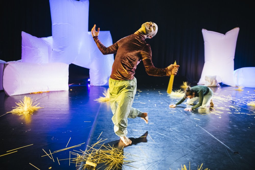 co>labs: Über(-)Dinge oder ein Himmel voller Pasta (ONLINE PREMIERE) - beim Veranstalter Im Vordergrund Tänzer Rouven Pabst lachend, im Hintergrund Tänzerin Juliane Bauer auf dem Boden knieend vor überdimensional großen weißen, kissenartigen Tüten