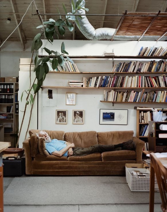Schaufensterausstellung Albrecht Fuchs: Album - Albrecht Fuch und VG Bildkunst Bonn, 2020 Älterer Mann liegt auf einem Sofa, das in einem Zimmer vor einer Wand mit Zimmerpflanze, Bildern und Bücherregalen steht