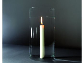 Foto einer brennenden Kerze, die scheinbar in einem Glas Wasser steht