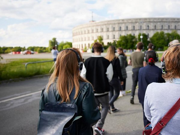 Wer ist wir? - Staatstheater Nürnberg Gruppe von Besucherinnen und Besuchern mit Kopfhörern vor der Kongresshalle