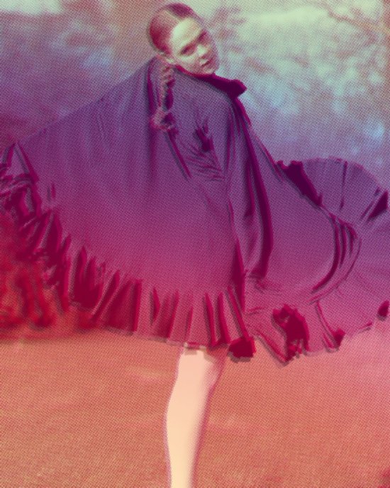 Tänzerin Eva Borrmann mit berüschtem Umhang blickt über die Schulter zum Betrachtenden; das Foto ist mit einem pink-lila Pixel-Filter bearbeitet