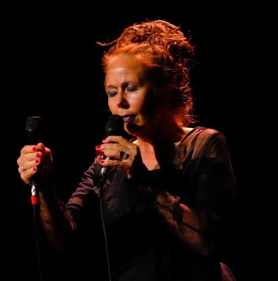 Die Sängerin Ruth Wilhelmine Meyer mit geschlossenen Augen am Mikrofon vor schwarzem Hintergrund