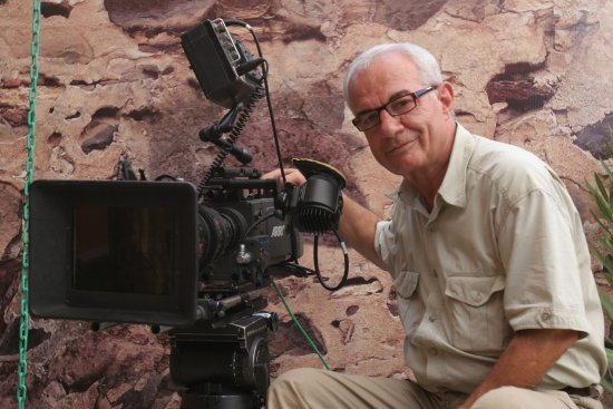 Serif Goeren sitzt vor einer Felswand neben seiner Filmkamera.