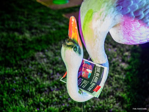Early-Bird-Special zur Blauen Nacht 2023 - Geschäftsbereich Kultur Im gekrümmten Hals eines Plastik-Schwans steckt ein Programmheft der Blauen Nacht.
