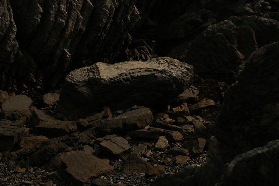 Auf der Abbildung sind spärlich beleuchtete Steine und Felsen in verschiedenen Formen und Größen zu sehen