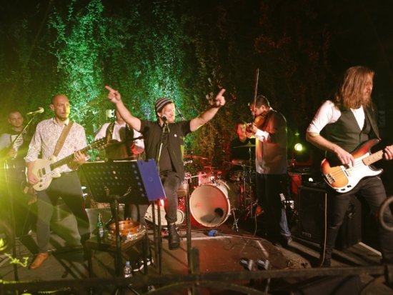 6 Musiker auf der Bühne in Aktion, grünes Licht im Hintergrund
