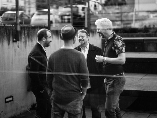 vier Männer lächelnd vor der abendlichen Tafelhalle