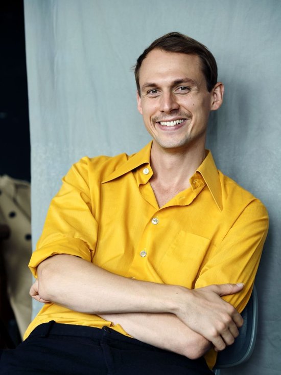 Porträtfoto des Schauspielers Yascha Finn Nolting mit gelbem Hemd vor grauem Hintergrund