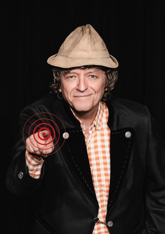 Mann mit hellbraunem Hut, lächelnd zeigt mit dem rechten Zeigefinger auf den Betrachter