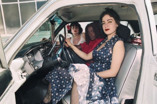 drei Frauen im Ausgehlook in einem Auto sitzend
