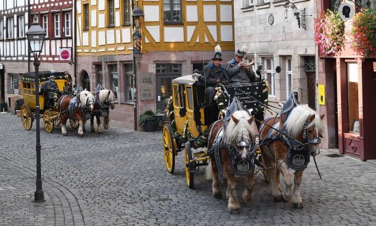 Historische Postkutsche mit zwei Pferden vor Fachwerkhäusern