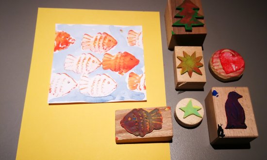 Verschiedene bunte Stempel und gestempelte Fische auf Papier