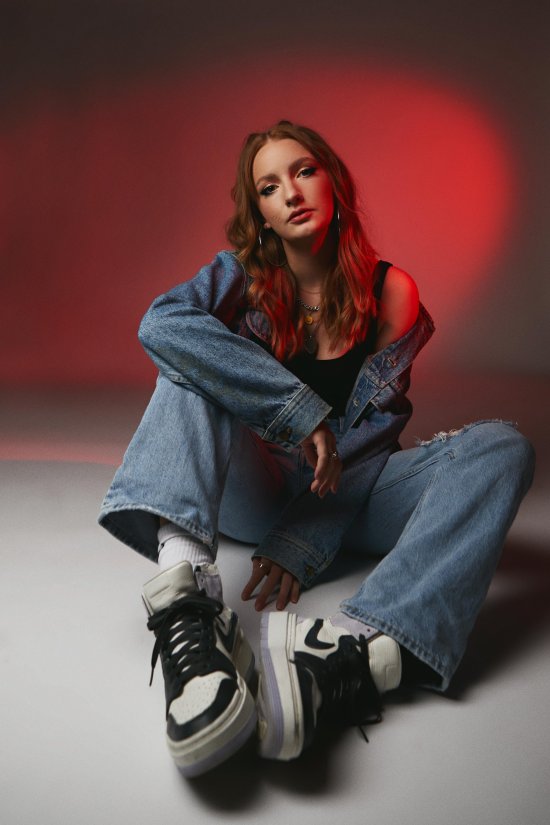 Cosima Kiby (in Jeans gekleidet) lässig auf dem Boden sitzend