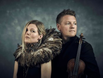 Portraitfoto von Helene Blum & Harald Haugaard vor einem blaugrauen Hintergrund, Harald Haugaard hält eine Violine