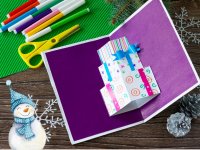 Eine gebastelte Weihnachts-Pop-Up Karte liegt offen auf einem Holztisch.