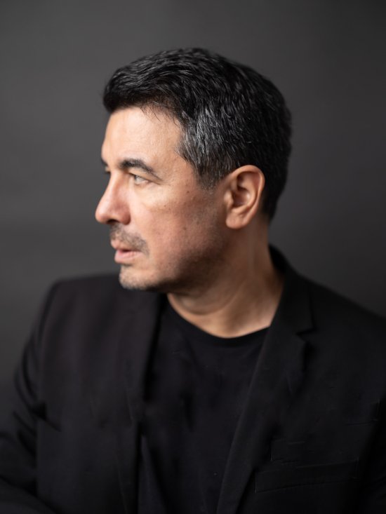Profilbild eines Mannes, kurze schwarze Haare, angegraute Schläfen, ernster Blick