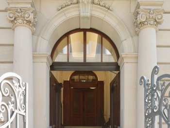 Repräsentativer Eingangsbereich der Kunstvilla mit breitem Rundbogenportal, korinthischen Pilastern, Freitreppe und geöffneten Holztüren.