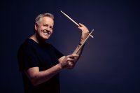 Lächelnder Mann im schwarzen T-Shirt mit Drum Sticks in den Händen