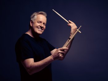 Lächelnder Mann im schwarzen T-Shirt mit Drum Sticks in den Händen