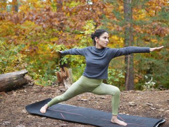 Copyright: Aakriti Rawat Frau auf Yogamatte im Wald, herbstlich gefärbte Blätter