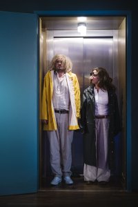 Zwei in pink gekleidete Personen, Mann + Frau, stecken eng aneinander gedrängt in einem riesigen aufblasbaren Flamingo