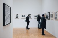 Drei Personen betrachten die ausgestellten Fotografien