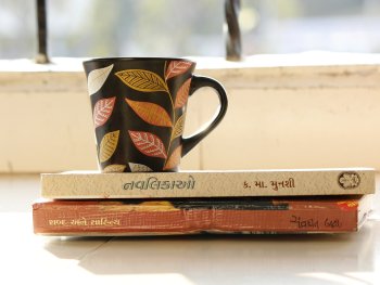 Tasse im Sonnenschein steht auf 2 Büchern