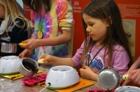 Foto eines jungen Kindes, das geschmolzene Schokolade in Pralinenförmchen gießt.