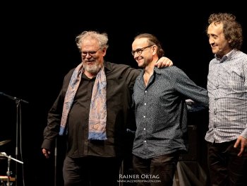 Copyright: Rainer Ortag
Das Trio stehend auf der Bühne, hat sich gegenseitig im Arm und lächeln.