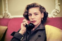 Schauspielerin Lauren Bacall telefoniert auf einer roten Couch sitzend