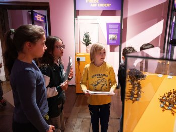 Kinder laufen durch die Ausstellung und halzen Rätselhefte in der Hand.
