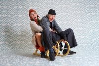 Zwei Schauspieler·innen als Wolf und Schaf verkleidet sitzen auf einem goldenen Schlitten, sie spielen eine wilde Schlittenfahrt.