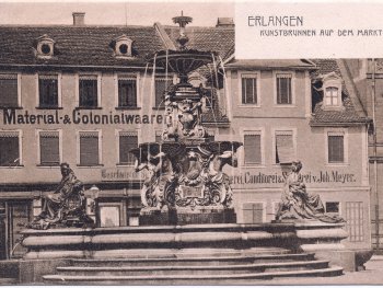 Kunstbrunnen auf dem Erlanger Marktplatz, im Hintergrund ein Colonialwarenladen