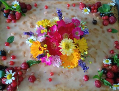 Ein Geburtstagskuchen mit vielen bunten Blüten oben drauf.