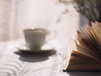 Foto: pixabay
Aufgeschlagenes Buch auf einem Tisch im Sonnenschein, im Hinter steht eine Porzellantasse