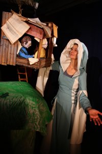 Anne und Philipp schauen aus dem Baumhaus seitlich zur Puppenspielerin