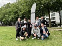 Acht Menschen stehen und hocken um ein Banner herum auf welchem "meet&street" zu lesen ist