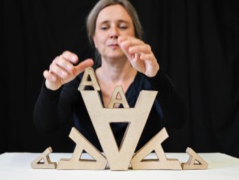 Im Vordergrund Pappbuchstaben gestapelt, im Hintergrund Kathrin Blüchert