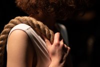 Nahaufnahme einer Person mit lockigem Haar, die ein dickes Seil über die Schulter legt und es mit der Hand hält.