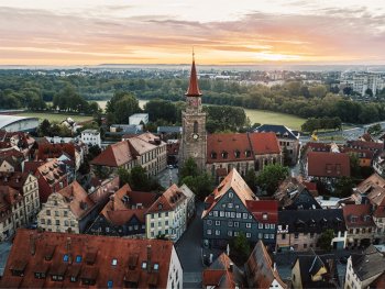 Luftaufnahme der Altstadt mit der Kirche St. Michael im Zentrum, umgeben von historischen Fachwerkhäusern bei Sonnenuntergang.