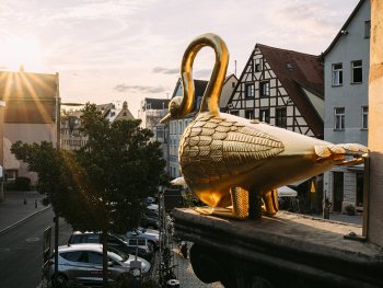 Figur "Goldener Schwan" als Wirtshausausleger am Grünen Markt, im Hintergrund Fachwerkhaus