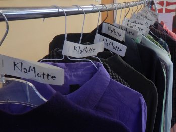 an einem Kleiderständer hängt Kleidung auf Bügeln