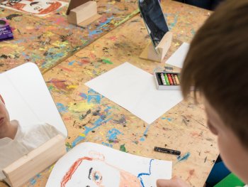 Foto: Erich Malter
Ein Junge sitzt vor einem Spiegel und zeichnet auf ein Blatt Papier sein eigenes Porträt.